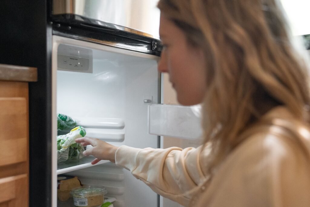 Woman experiencing evening sugar cravings while looking in a fridge.