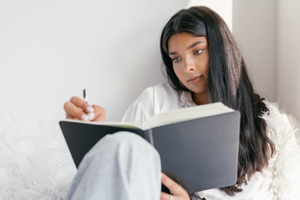 Self-reflective woman writing in journal to replace inner criticism with positive affirmations.